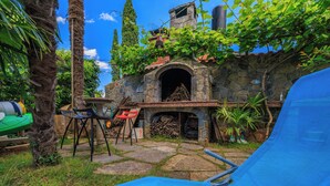 Un edificio in pietra con un camino, una poltrona blu e un piccolo tavolo con sedie.