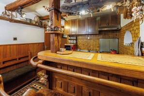 Eine rustikale Küche mit Holzschnitzereien, einem eingebauten Herd und einer Darre mit Maiskolben.