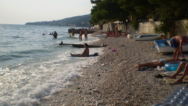 A pebbled beach with people sunbathing and swimming. - Apartments Kate (Gradac)