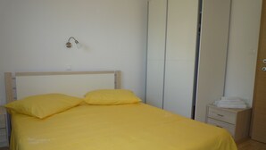 A bed with a yellow bedspread and pillows, a bedside table with a lamp, and a wardrobe with a mirror. - Apartments Kate (Gradac)