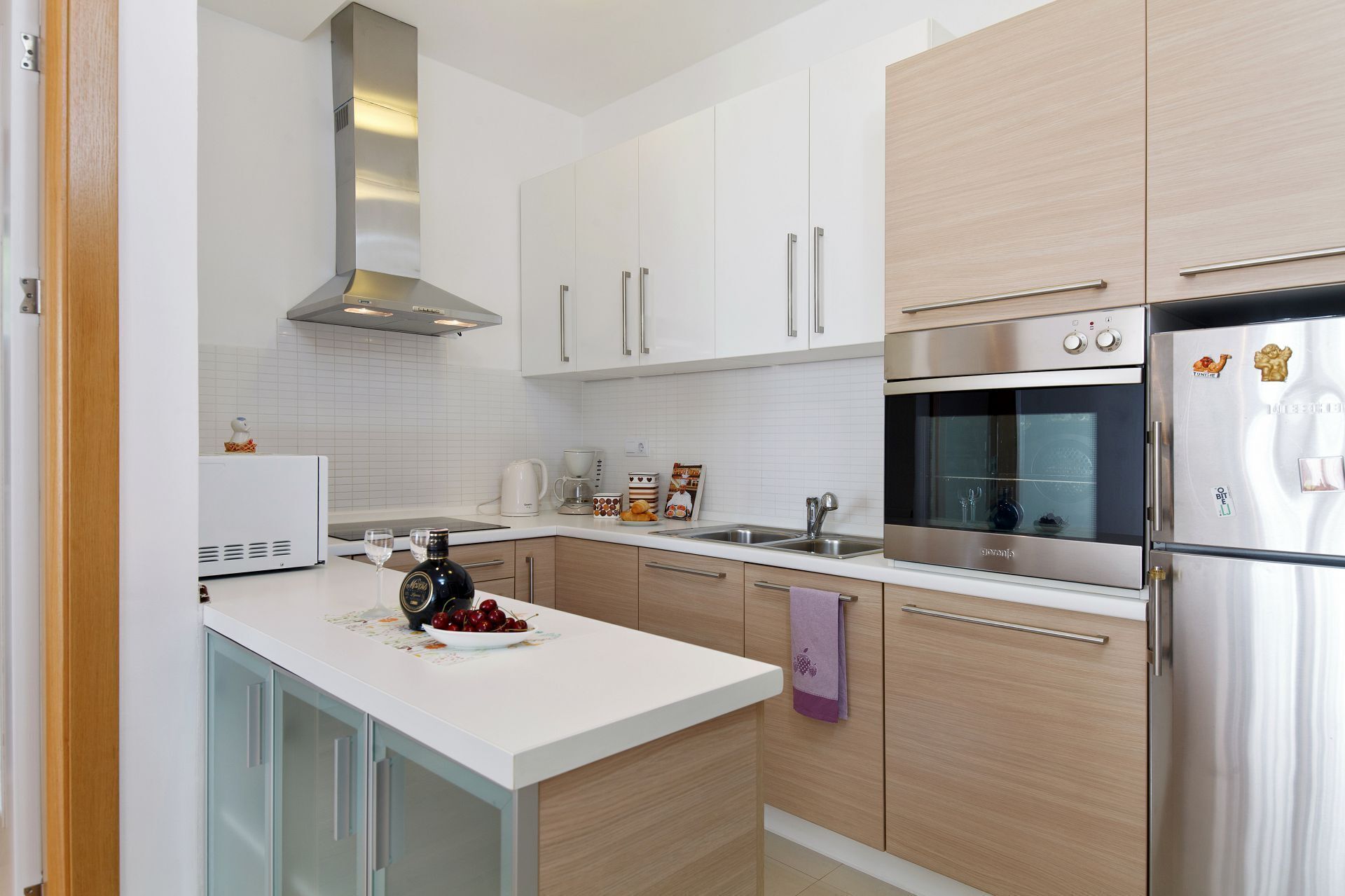A modern kitchen with white cabinets, stainless steel appliances, and a central island with a purple towel.