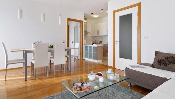 Un soggiorno moderno con un tavolino in vetro, un divano e una zona pranzo con sedie.