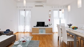 Un soggiorno moderno con una televisione a schermo piatto, un'area pranzo con tavolo e sedie e un divano.