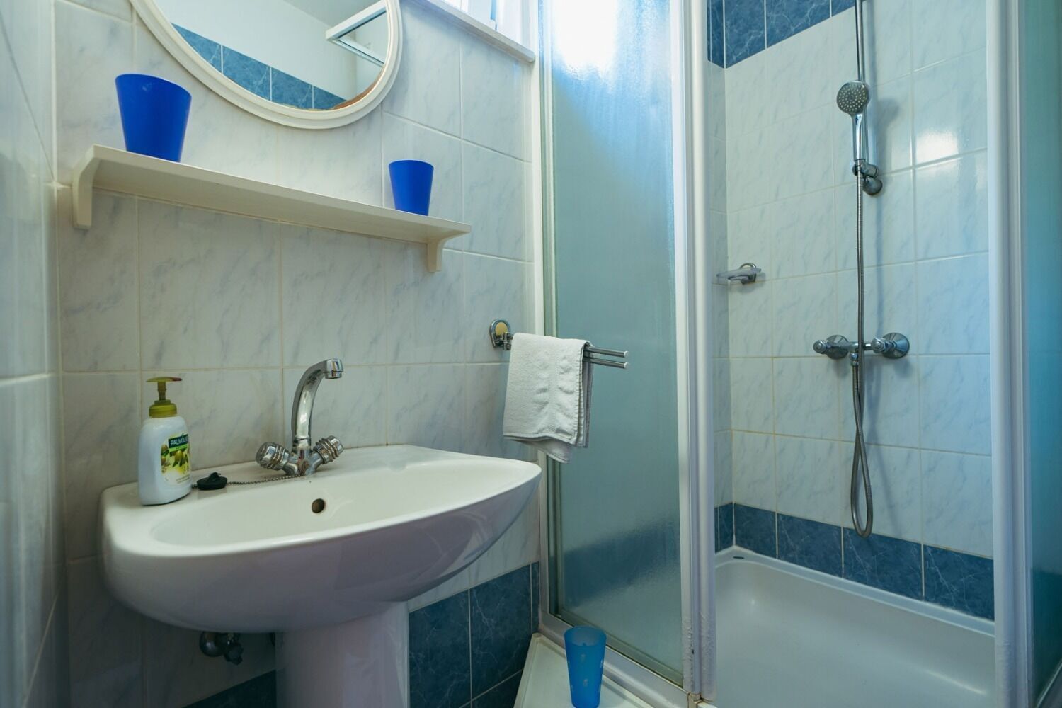 A bathroom with a sink, mirror, and shower.