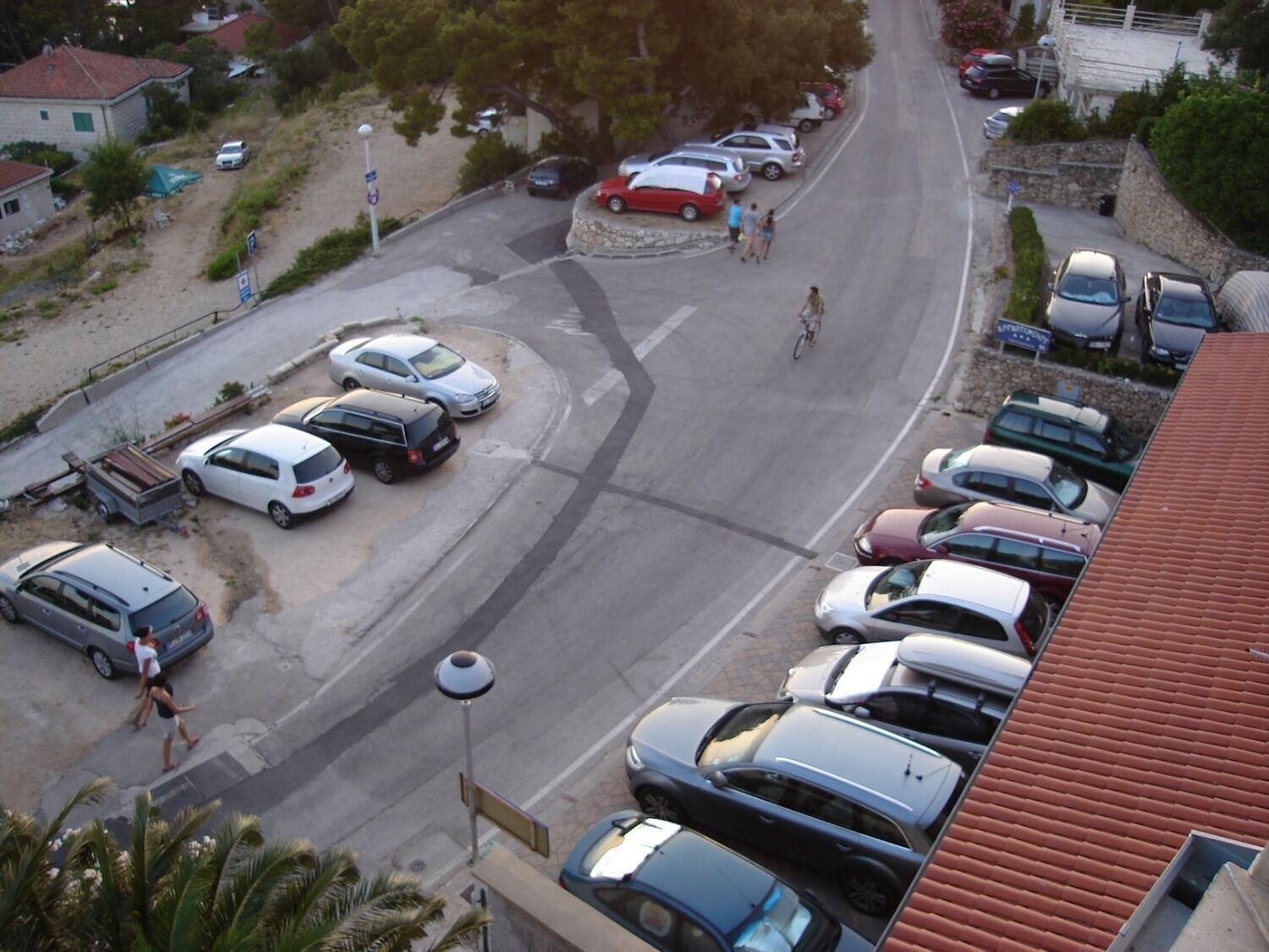 A parking lot with multiple cars and a few pedestrians.