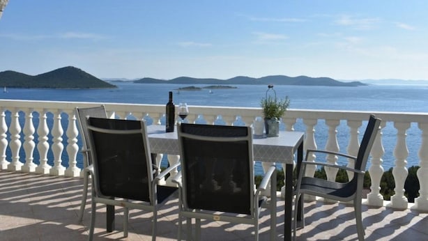 Ein Balkon mit Tisch und Stühlen mit Blick auf das Meer.