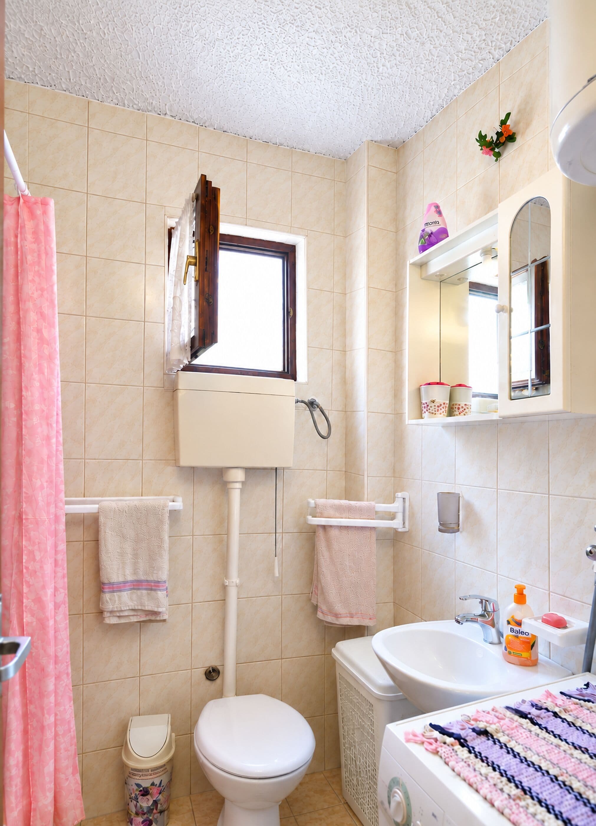 Een badkamer met toilet, wastafel en raam.