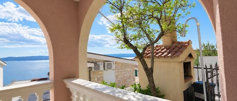 A balcony with a view of the sea and a tree.