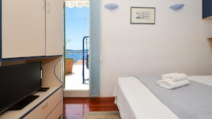Une chambre à coucher avec un lit, une télévision et une vue sur un balcon doté d’une balustrade.