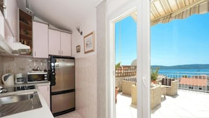 Une cuisine équipée d’appareils électroménagers modernes et un balcon avec vue sur la mer.