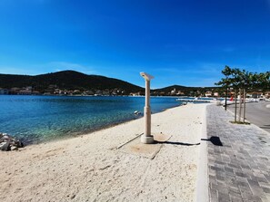 Ein Küstenweg mit freiem Blick auf das Meer und einem entfernten Berg.