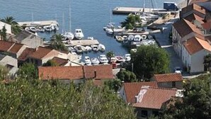 En lystbådehavn med fortøjede både, omgivet af boligbygninger med rødt tegltag.