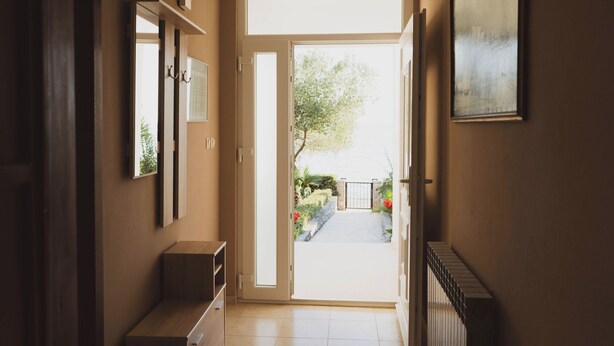 Un couloir avec une porte donnant sur un jardin.