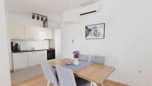 Une cuisine moderne avec des meubles blancs, une table à manger en bois et des chaises grises.