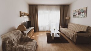 Un salon moderne avec un canapé, une table basse, un téléviseur et une lampe.