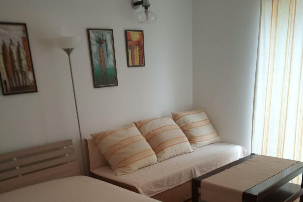 Ein Zimmer mit zwei Betten, einer Bank und einer Wandleuchte.