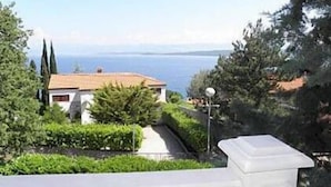 A coastal view with a white building, a pathway, and greenery. - Apartments Pondeljak (Malinska-Dubasnica)