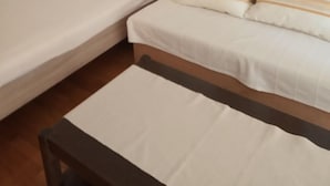 A bedroom with two single beds, a bedside table, and a floor lamp. - Apartments Pondeljak (Malinska-Dubasnica)