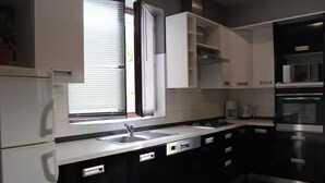 Ett modernt kök med en inbyggd ugn, en mikrovågsugn och en diskho.