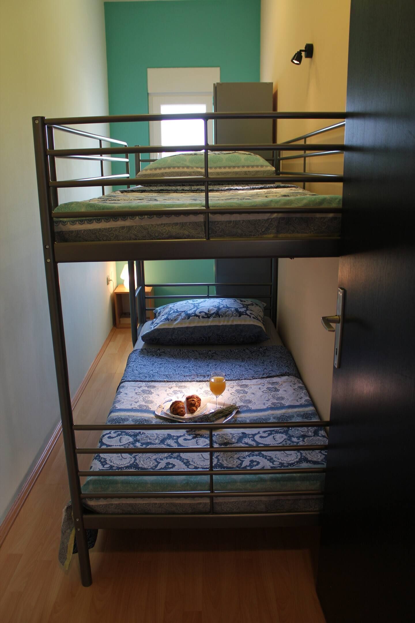 A bunk bed with a tray of cookies and a glass of juice on the lower bunk.