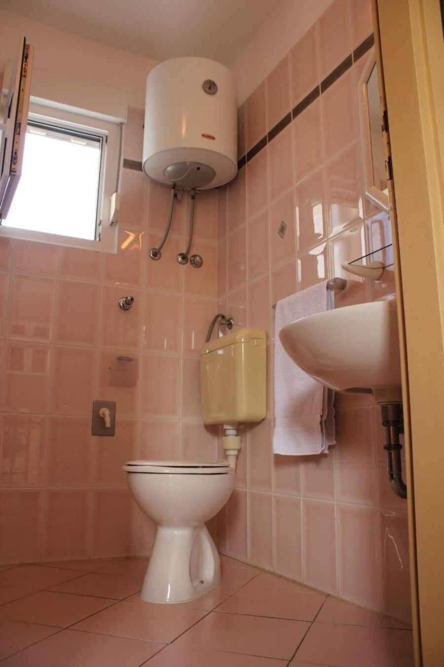 A bathroom with a toilet, a sink, a towel rack, and a window.