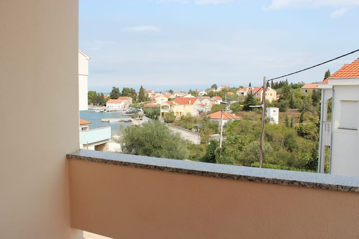 A balcony with a view of a residential area, including houses and a body of water.