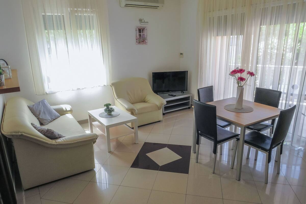A living room with a sofa, TV, and dining area.