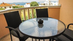 A round glass table with two chairs on a balcony overlooking a cityscape. - Apartments Eddie (Zadar)