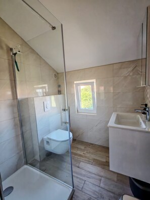 A modern bathroom with a glass shower enclosure, a toilet, and a sink. - Apartment Ivy (Kukljica)