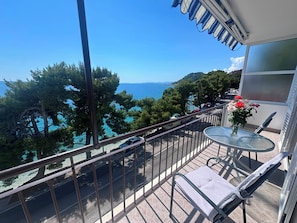 Ein Balkon mit Glastisch, Stuhl und Blumenvase.