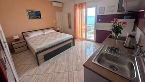 A bedroom with a bed, bedside tables, a nightstand, a window with curtains, and a view of the sea. - Apartment Verica (Dugi Rat)