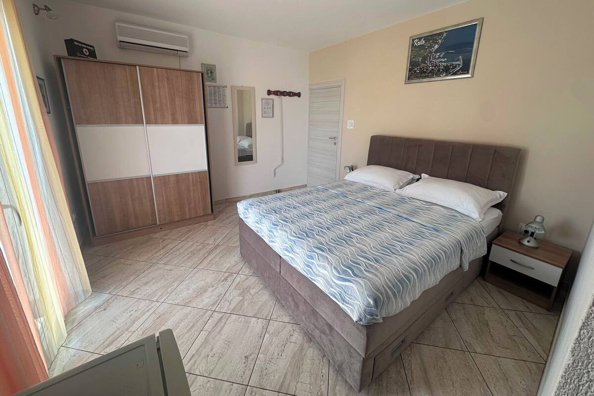 A bedroom with a bed, a nightstand, a wardrobe, and a wall-mounted air conditioner.