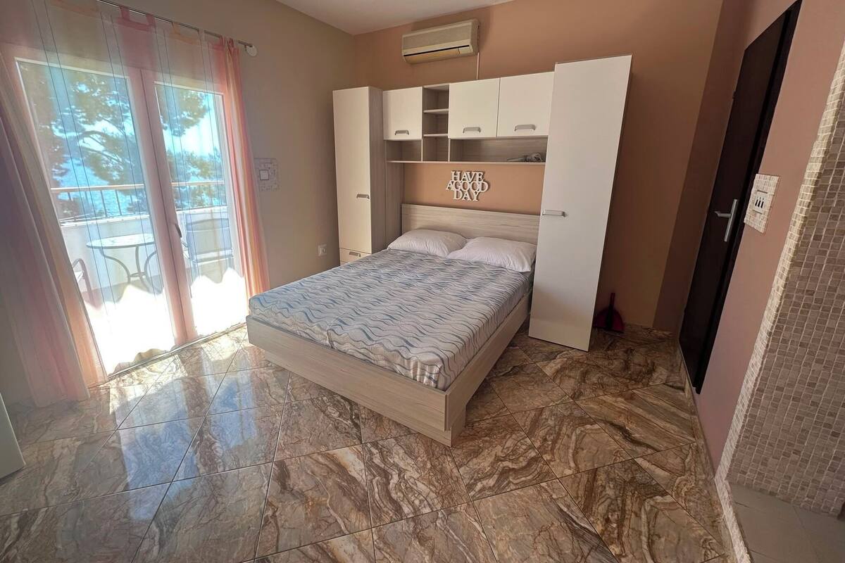 A bedroom with a bed, built-in wardrobe, and a view through a window.