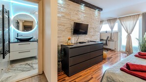 A modern bathroom with a marble vanity, a round mirror with LED lights, and a black sink.