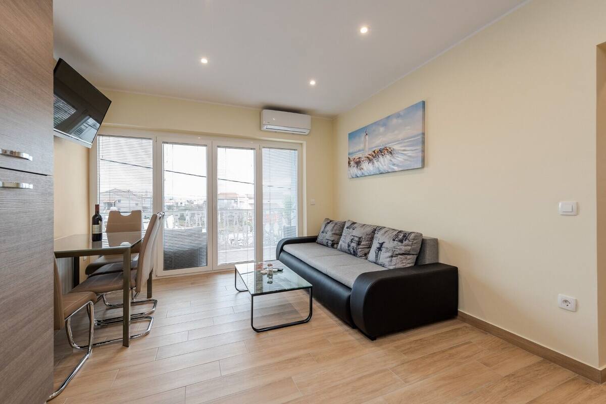 A modern living room with a glass coffee table, a sofa, and a dining area with chairs.
