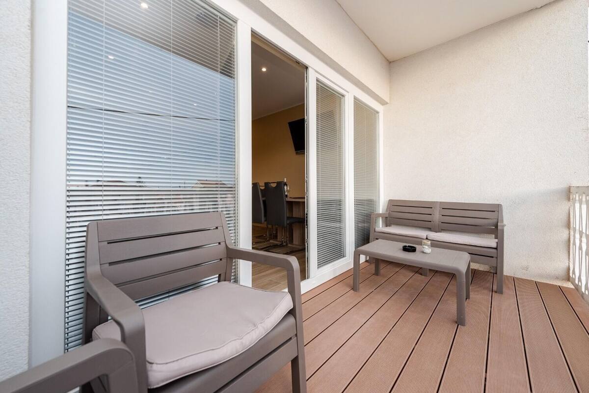 A balcony with a wooden floor, a grey bench, and a table with a candle.