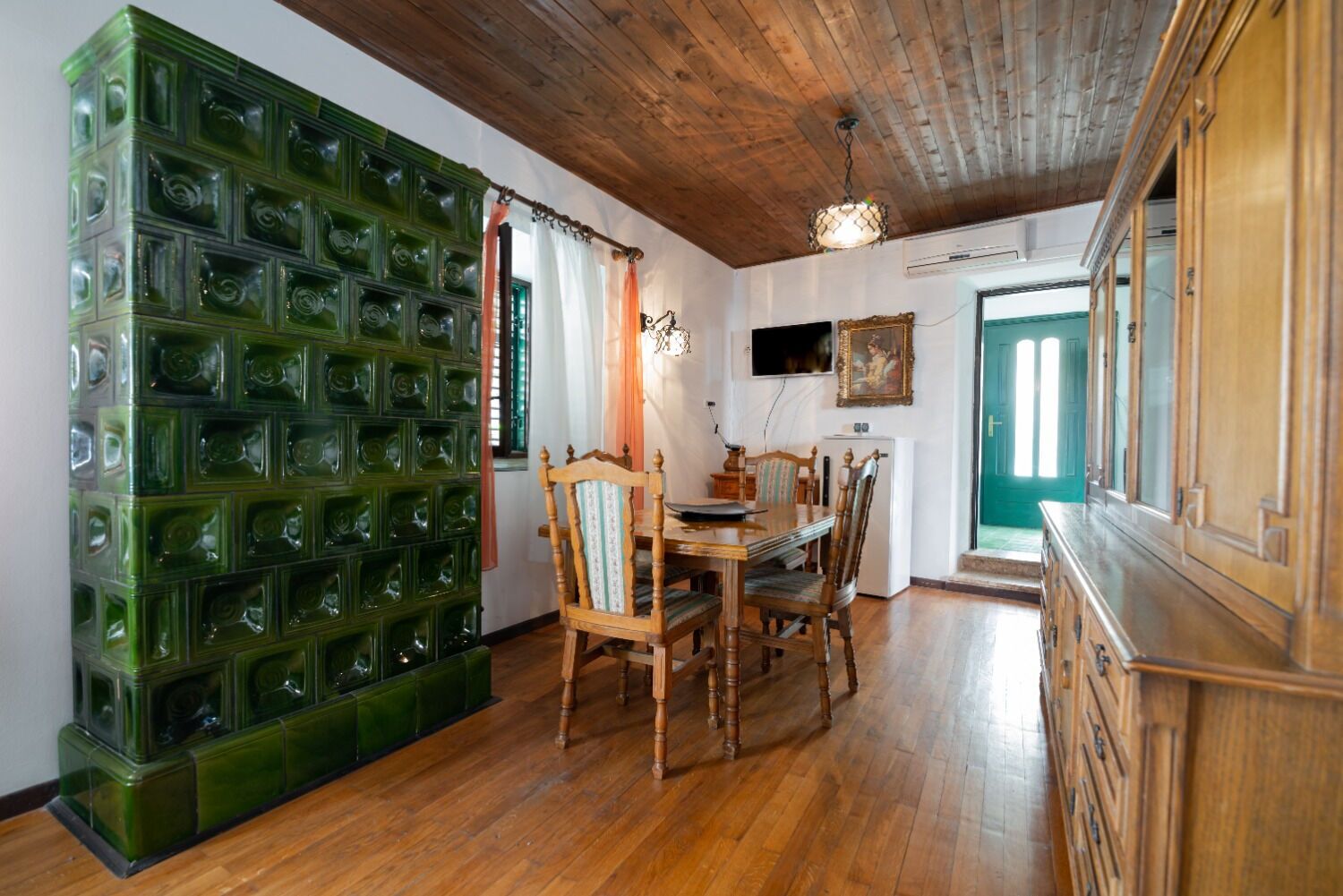 Un coin repas avec une table en bois, des chaises et un mur décoratif vert.