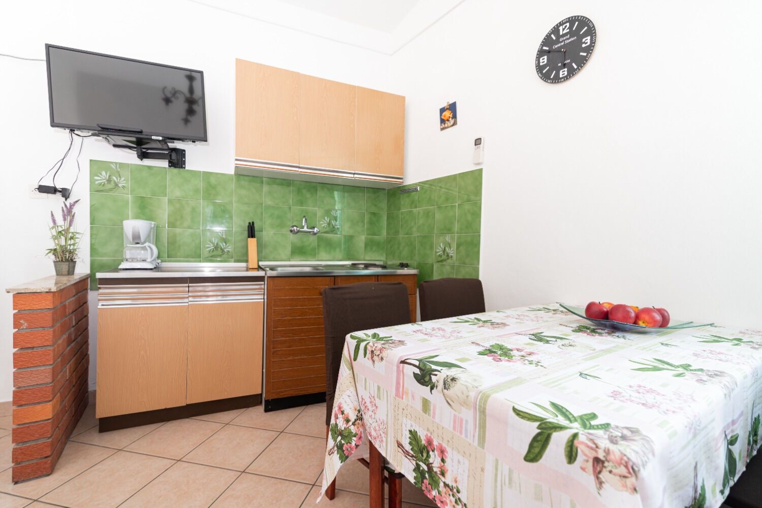 A compact kitchen with a coffee maker, sink, and a clock on the wall.