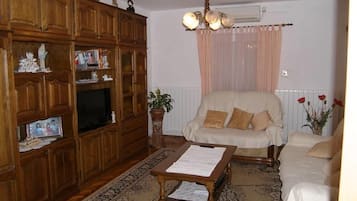 A living room with a wooden cabinet, a television, a beige sofa, and a patterned rug.