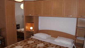 A bedroom with a bed, wooden wardrobe, and a bedside table with a lamp. - Apartments Mirko (Tkon)