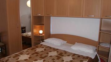 A bedroom with a bed, wooden wardrobe, and a bedside table with a lamp.