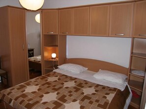 A bedroom with a bed, wooden wardrobe, and a bedside table with a lamp. - Apartments Mirko (Tkon)