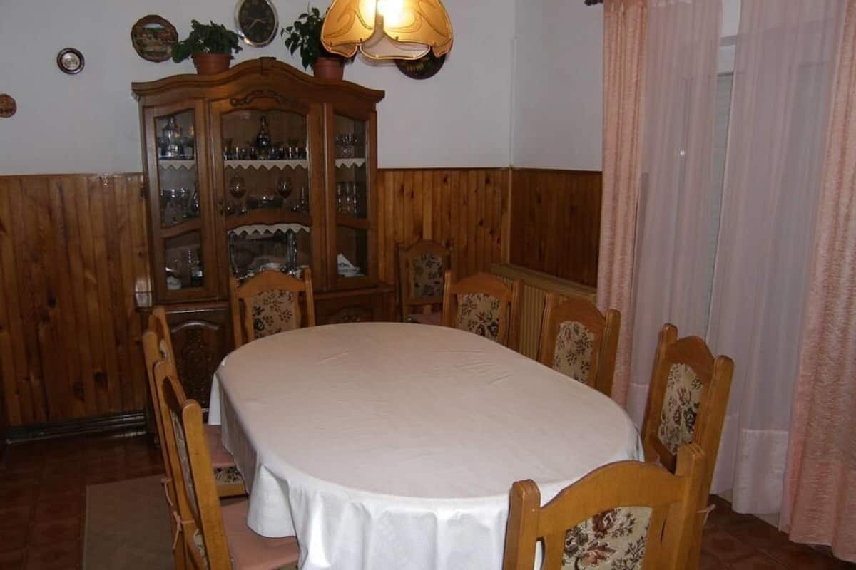 A dining room with a round table, wooden chairs, a cabinet with glass doors, and a chandelier.