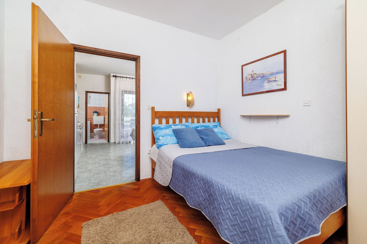 Un dormitorio con una cama de madera, una colcha azul y un cabecero de madera.