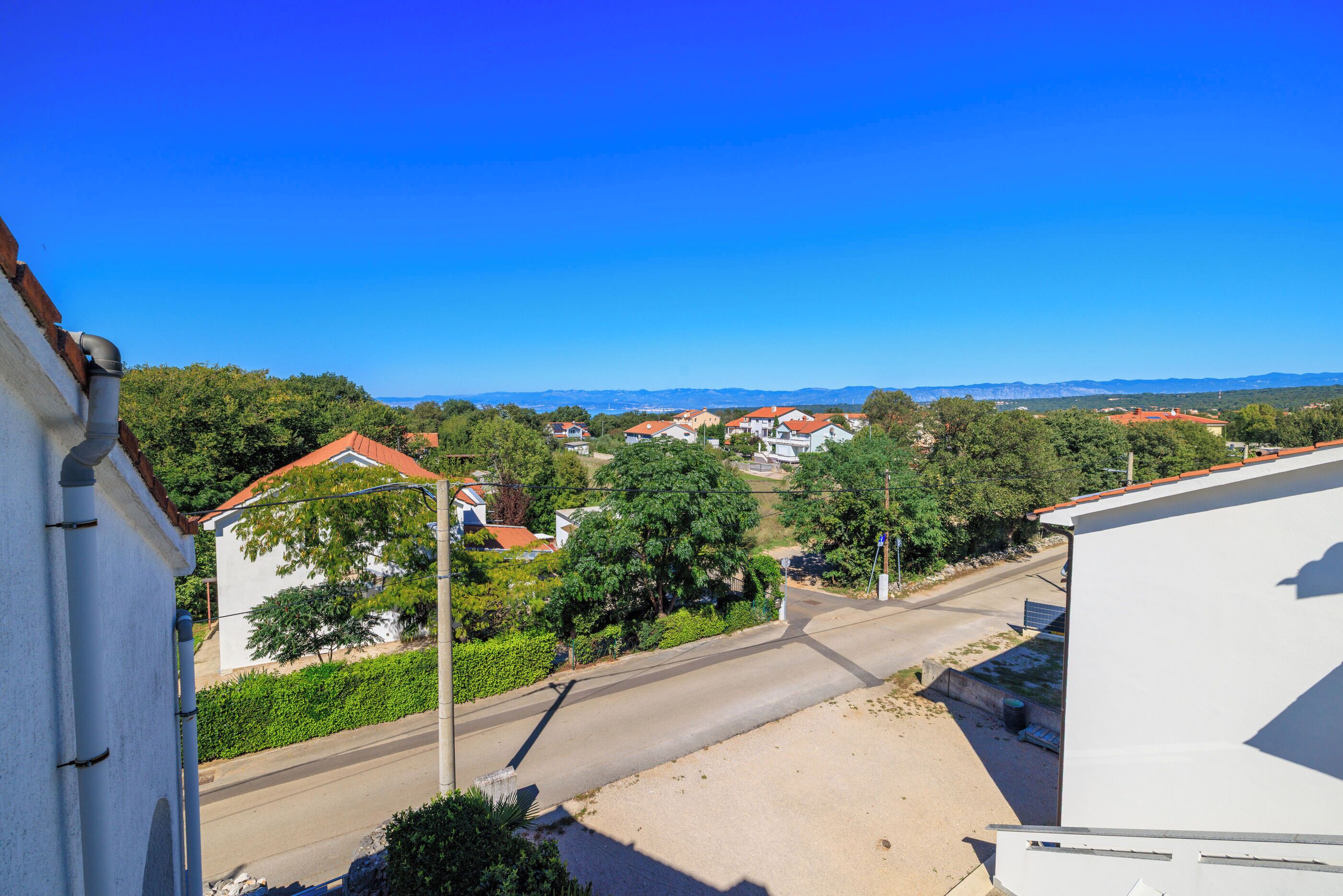 A residential area with houses, a clear sky, and a road.