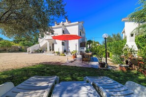 A white building with a red umbrella, outdoor seating, and potted plants. - Apartment Dragica (Malinska-Dubasnica)