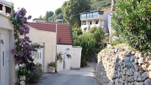 A narrow street with a stone wall on one side and a building with a red roof on the other. - Apartment Inga (Gradac)