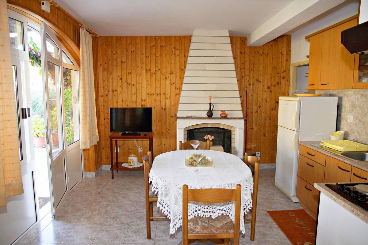 Eine gemütliche Küche mit Holzwänden, einem Kamin, einem Esstisch mit Stühlen und einem Fernseher.