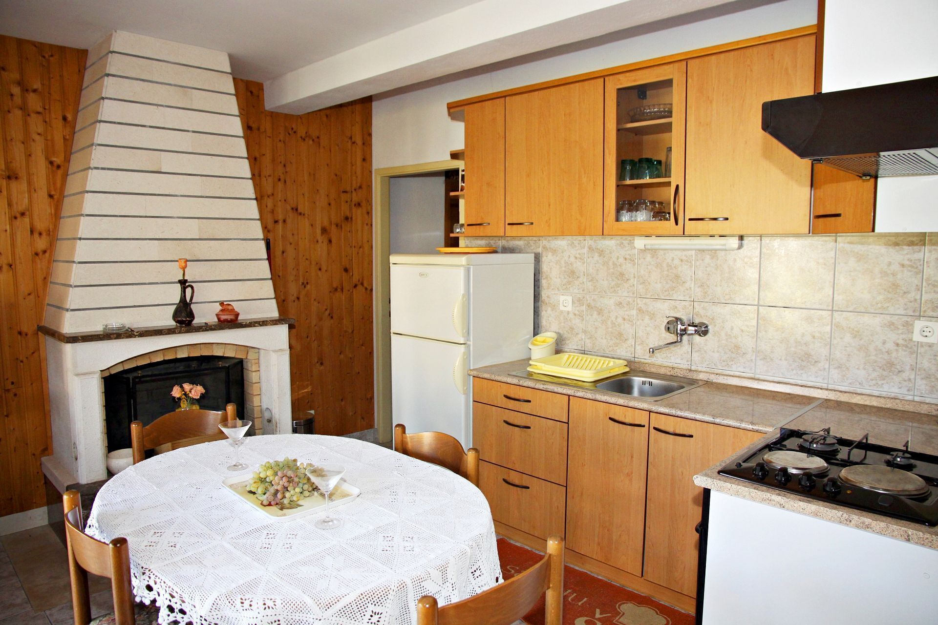 A kitchen with wooden cabinets, a white refrigerator, a gas stove, and a fireplace with a white mantel.