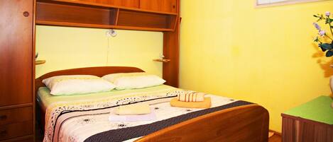 Un dormitorio con cama de madera, una mesita de noche y una ventana con persianas.